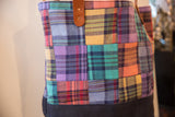 Colorful plaid patchwork squares and brown leather handle on the vintage tote bag.