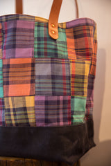 Angled view of the plaid patchwork tote showing varied fabric and black canvas base.