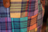 Detail of the stitching joining colorful squares of vintage plaid patchwork fabric.