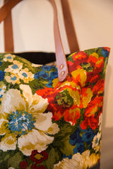 Market tote bag's vintage floral fabric with a bright, colorful pattern and leather strap.