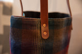 Vintage gradient plaid tote with brown leather strap, copper rivets, and deep multi-toned fabric.