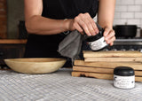 Restoring wood kitchen items by hand using Bartram Wood Balm and a soft cloth.