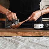 Applying Bartram Wood Balm to a wooden spoon with a soft cloth to restore its finish.