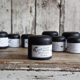 Peg & Awl Bartram Wood Balm in a matte black jar with a white botanical label.