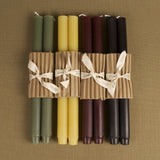 An assortment of pure beeswax church taper candles in celadon, yellow, burgundy, and black.