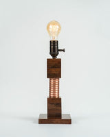 Edison lamp featuring a glowing bulb, dark oak wood base, and spiral copper coil.
