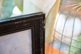 Ornate, distressed black frame corner with chipping paint on Keogh painting.