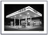 Black and white photograph of a Hess Gas Station in New York, brightly illuminated at night.