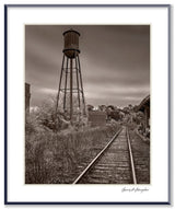 A black and white photograph of a water tower and railroad tracks in Housatonic, Massachusetts.