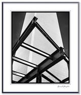 Low-angle black and white photograph of the World Trade Center framed by steel construction beams.