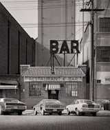 Street view of a downtown New York bar's brick storefront, awnings, and large rooftop sign.