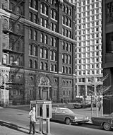 Ornate historic building facade contrasted with a modern geometric skyscraper in a black and white photo.