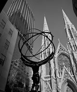 Low-angle black and white photo showing the Atlas statue with St. Patrick's Cathedral spires.