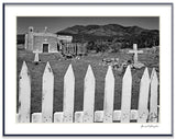Black and white photograph of the San Francisco Church in New Mexico, with a white picket fence in the foreground.