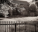 Black and white photographic detail of an old barn's weathered wood siding and roofline.