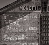 Angled view of a weathered wall with a faded, painted Levi Strauss Overalls advertisement.