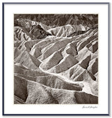 A framed black and white photograph of the Zabriskie Badlands, showing textured, layered desert hills.