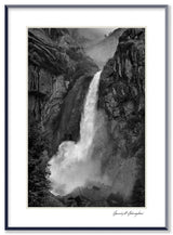 A framed black and white print of Yosemite Falls, with water cascading down a dramatic, misty rock face.