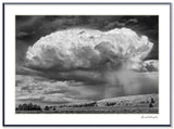 Dramatic black and white photograph of a storm cloud raining over a rolling Wyoming landscape.
