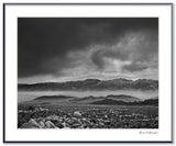 A dramatic black and white photograph of a storm over California's misty Inyo Range.