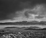 Dramatic contrast between the rocky valley floor and the misty Inyo Range in black and white.