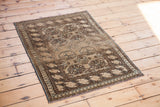 Vintage Bokhara rug corner with geometric patterns in golden charcoal and muted blue.