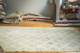 Distressed vintage Oushak carpet, blanched with muted green angular clover motifs.
