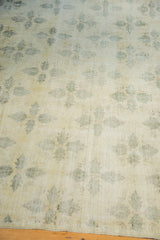 Distressed Oushak carpet revealing blanched texture and faded green clover pattern.