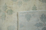 Distressed Oushak rug showing blanched pile, faded green clover pattern, and woven foundation.