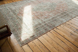 Distressed Oushak carpet corner with faded blanched rust and green hues.
