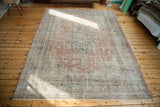 Faded blanched rust and ivory border patterns on the distressed Oushak carpet corner.