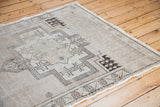 Corner of vintage Oushak rug featuring bold geometric patterns and light beige tones.