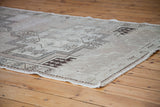 Vintage Oushak rug detail showing geometric pattern in neutral beige with worn edge.