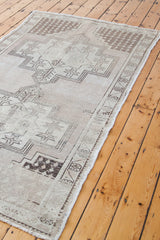Vintage Oushak rug corner with geometric border, light neutral pile, and soft fringe.