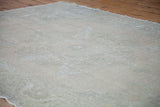 Vintage Oushak rug showing subtle faded patterns and low, thin pile texture in light tones.