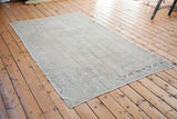 Vintage Oushak rug corner displaying subtle faded motifs and airy texture.