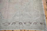 Hand-knotted vintage Oushak rug corner, light fringe, muted patterned border.