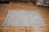 Light, airy vintage Oushak rug in soft beige tones with subtle curvilinear pattern.