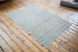 White serged edge and subtle light green-beige pile of the vintage Oushak rug.