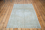 Fringed edge detail of a vintage Oushak rug, showing subtle light green tones and faded patterns.