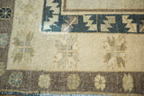 Cream field of vintage Oushak rug with subtle sage geometric motifs and a dark teal border.