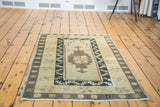 Geometric brown and muted blue patterns on a soft beige vintage Oushak rug.