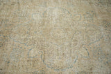 Distressed texture of a vintage Oushak rug, with faded beige and muted blue patterns.