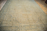 Faded blue-green border patterns on the distressed light beige Oushak rug.