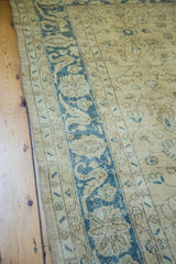 Sweeping blue border design on a distressed Oushak carpet with faded floral field.
