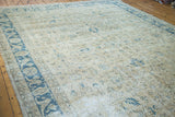 Distressed Oushak carpet: airy beige field, faded blue floral design, sweeping border.