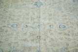 Distressed Oushak carpet pile showcasing faded sprawling floral motifs in light beige and blue.