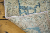 Distressed Oushak carpet showing muted beige pile, hand-knotted reverse, and pink serged edge.