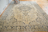 Light vintage Oushak carpet featuring a faded central medallion and bold dark outlines.