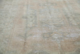 Distressed Oushak carpet's textured pile, with soft beige and slate green faded patterns.